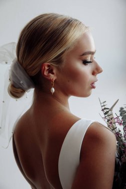 Çekici genç gelinin portresi güzel bir düğün buketi tutuyor.               