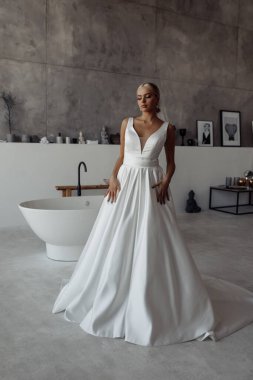 Modern banyo içinde poz veren beyaz gelinlik içindeki güzel genç gelinin portresi.      