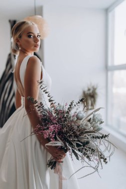 Çekici genç gelinin portresi güzel bir düğün buketi tutuyor.               