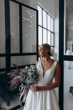 Çekici genç gelinin portresi güzel bir düğün buketi tutuyor.               