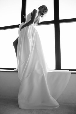 Zarif saç stili olan, gelinlik giyen ve içeride poz veren güzel bir gelin.        