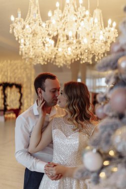 Güzel, zarif, birbirine aşık bir çift. Sıcak, şenlikli bir iç mekanda kucaklaşıyorlar.