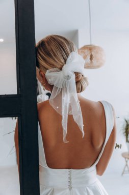 Zarif saç stili olan, gelinlik giyen ve içeride poz veren güzel bir gelin.        