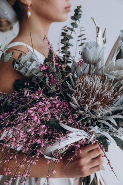 Çekici genç gelinin portresi güzel bir düğün buketi tutuyor.               