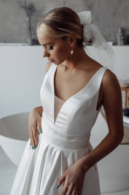 Modern banyo içinde poz veren beyaz gelinlik içindeki güzel genç gelinin portresi.      