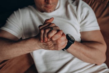 Akıllı saatli genç adamın evdeki kanepede otururken çekilmiş görüntüsü.