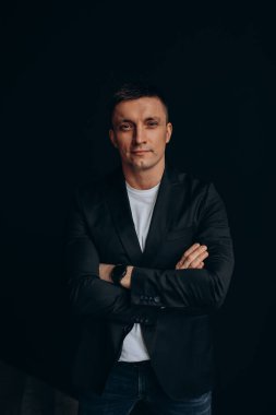 Stüdyoda karanlık arka planda poz veren yakışıklı bir adamın portresi.       