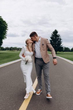 Mutlu genç bir çift parkta yürüyor ve öpüşüyor.