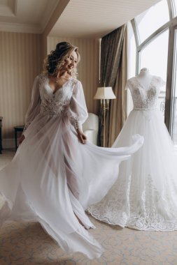 Beyaz dantelli gelinlik içinde mutlu genç gelin sabah evde dans ediyor.