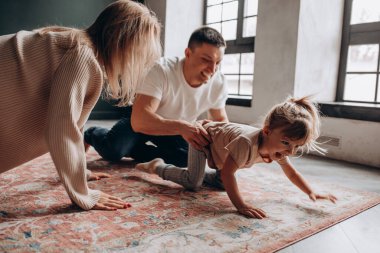 Mutlu ebeveynler küçük kızlarıyla oturma odasında oynuyorlar.. 