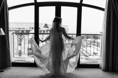 Pencere kenarında poz veren çekici genç gelinin arka planı, siyah ve beyaz