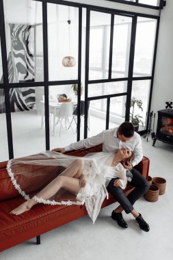 Birbirlerine aşık güzel bir çift stüdyoda kırmızı kanepe, gelinlik giyen bir kadın.. 