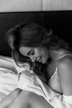 çekici genç bir kadın yatakta oturuyor ve gülüyor, siyah beyaz.