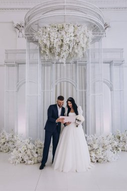 Mutlu gelin ve damat düğün gününde gülümsüyor ve birlikte duruyorlar.