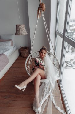 Düğün ayakkabıları ve duvak takan ve salıncakta sallanan genç bir kadın.