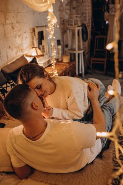 Genç çift Noel 'de odada dinleniyor ve birbirlerine sarılıyorlar.