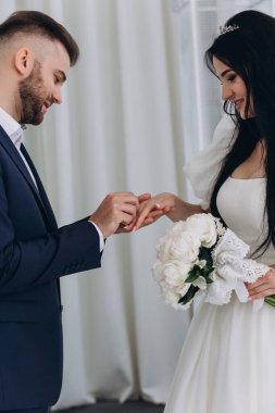 Genç gelin ve damat törende alyanslarla el ele tutuşuyorlar.