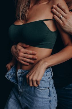  Stüdyonun karanlık odasında flört eden çift. Erkek kadının karnına dokunuyor, kırpılmış görüntü. 