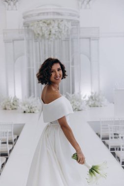 Zarif gelinlik içinde güzel bir buket çiçek taşıyan çekici bir gelinin portresi.                      