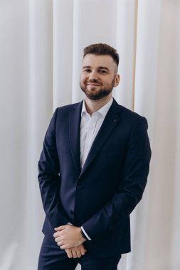 Takım elbiseli yakışıklı adamın portresi stüdyoda kameraya gülümsüyor.