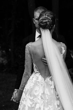 Güzel bir düğün çifti sarılıp el ele tutuşuyor, siyah ve beyaz.