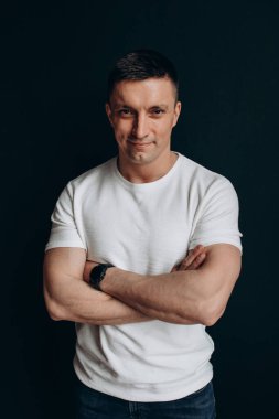 Stüdyoda karanlık arka planda poz veren yakışıklı bir adamın portresi.       