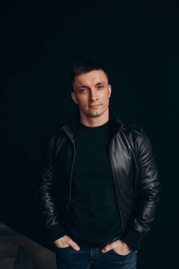 Stüdyoda karanlık arka planda poz veren yakışıklı bir adamın portresi.       