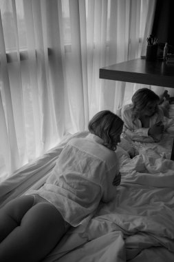 Genç, güzel bir kız yatakta uzanıyor, siyah beyaz.
