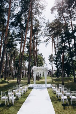 Güzel çiçekli düğün kemeri ve parkta boş sandalyeler.