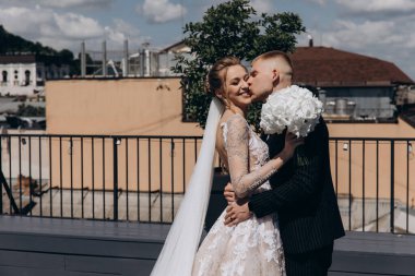 Mutlu genç gelin ve damat şehirde sarılıp öpüşüyor.