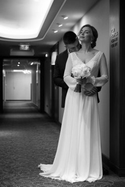 Güzel bir düğün çifti otel koridorunda sarılıp öpüşüyor.