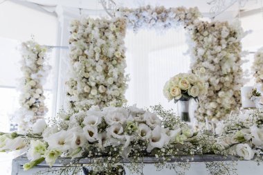 Beyaz bir salonda bir sürü çiçekli lüks düğün resepsiyonu 