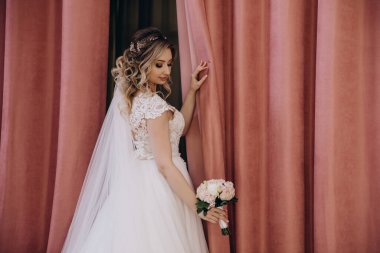 Zarif gelinlik içinde güzel bir buket çiçek taşıyan çekici bir gelinin portresi.                      