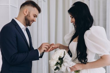 Genç gelin ve damat törende alyanslarla el ele tutuşuyorlar.