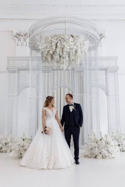 Gelin ve damat düğün stüdyosunda birbirlerine poz verip gülümsüyorlar.