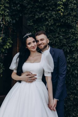 Mutlu gelin ve damat kameraya sarılıp poz veriyorlar. 