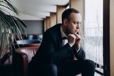 İçerde poz veren zarif kıyafetli yakışıklı damadın portresi.        