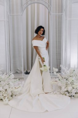 Stüdyoda poz veren zarif gelinlik içinde güzel genç bir gelin.          