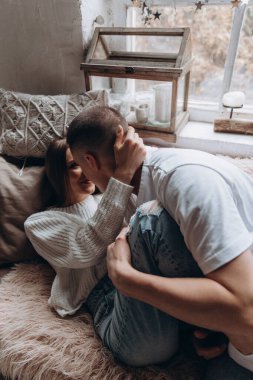 Genç çift stüdyoda yatakta öpüşüyor.