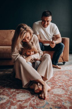 Kahverengi kanepenin stüdyosunda mutlu bir aile. Anne, baba ve kızı.