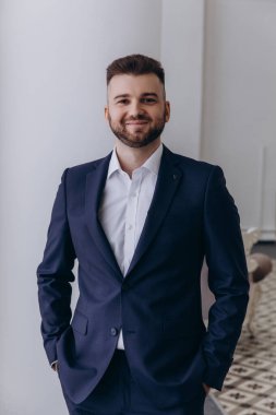 Stüdyoda poz veren şık takım elbiseli yakışıklı damadın portresi.       