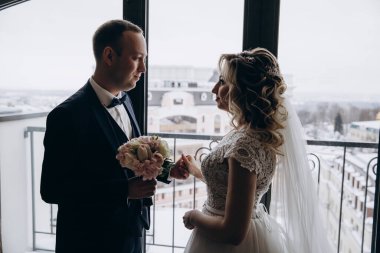 Pencere kenarında durup birbirlerine bakan güzel çiftin yan görüntüsü.