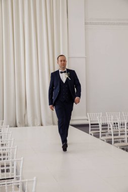 Stüdyoda poz veren şık takım elbiseli yakışıklı damadın portresi.       