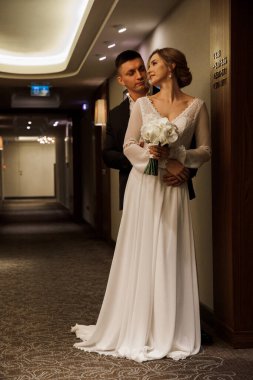 Otel salonunda poz veren mutlu gelin ve damat.