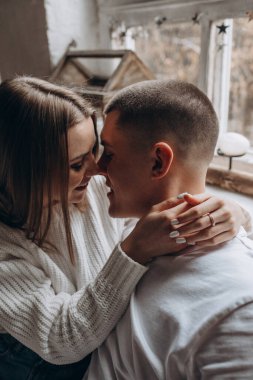 Bir çift pencereli odada oturuyor ve öpüşüyorlar. 