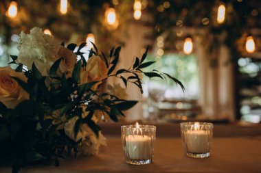 Mumlar ve çiçeklerle süslenmiş düğün masası, yakın plan.