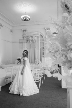 Çekici, mutlu, gelinlik içinde, elinde bir buket çiçek tutan genç gelin.            