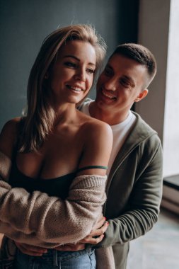 Mutlu gülümseyen beyaz çift stüdyoda kucaklaşıyor. 