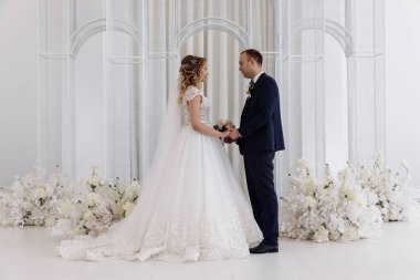 Gelin ve damat el ele tutuşup düğün töreninde birbirlerine bakıyorlar.