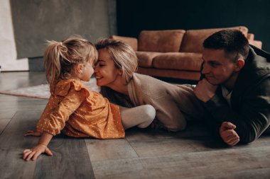 Küçük tatlı kızı olan genç ebeveynler birlikte vakit geçirip evde oynuyorlar.       